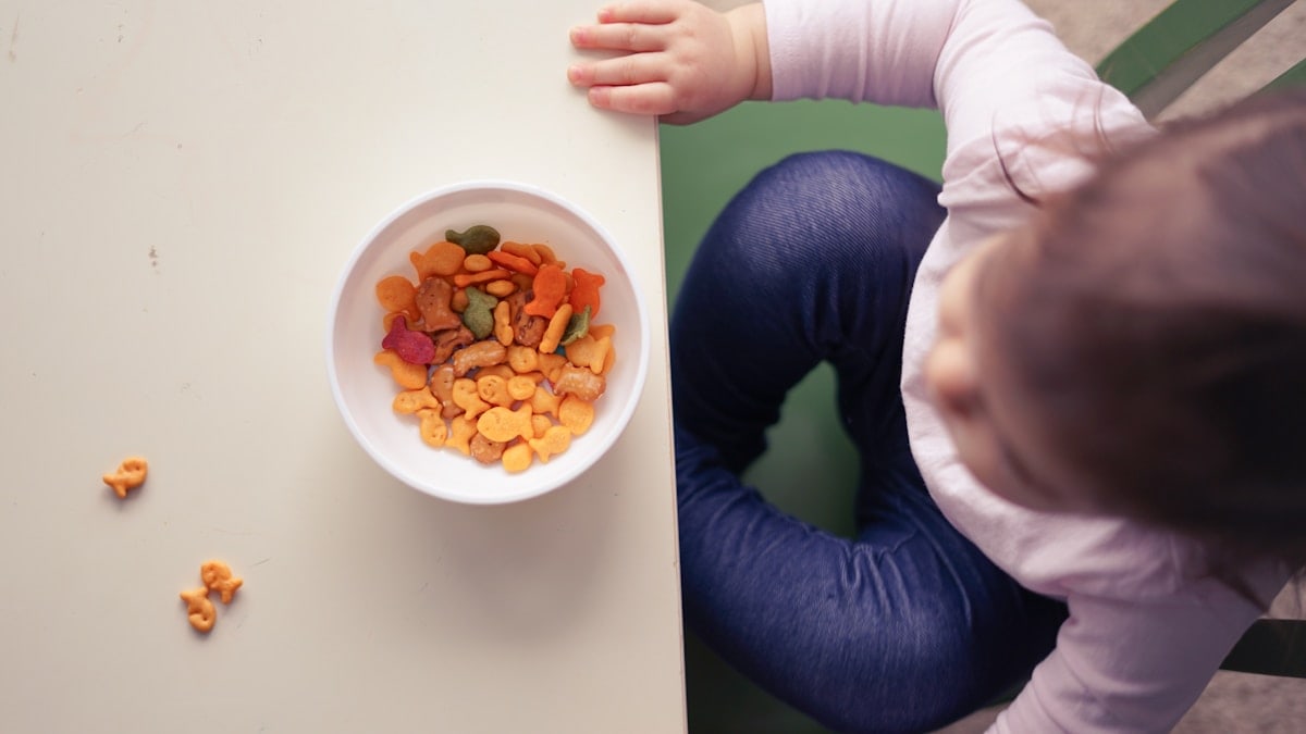 toddler sitting in front of bowl on top of table